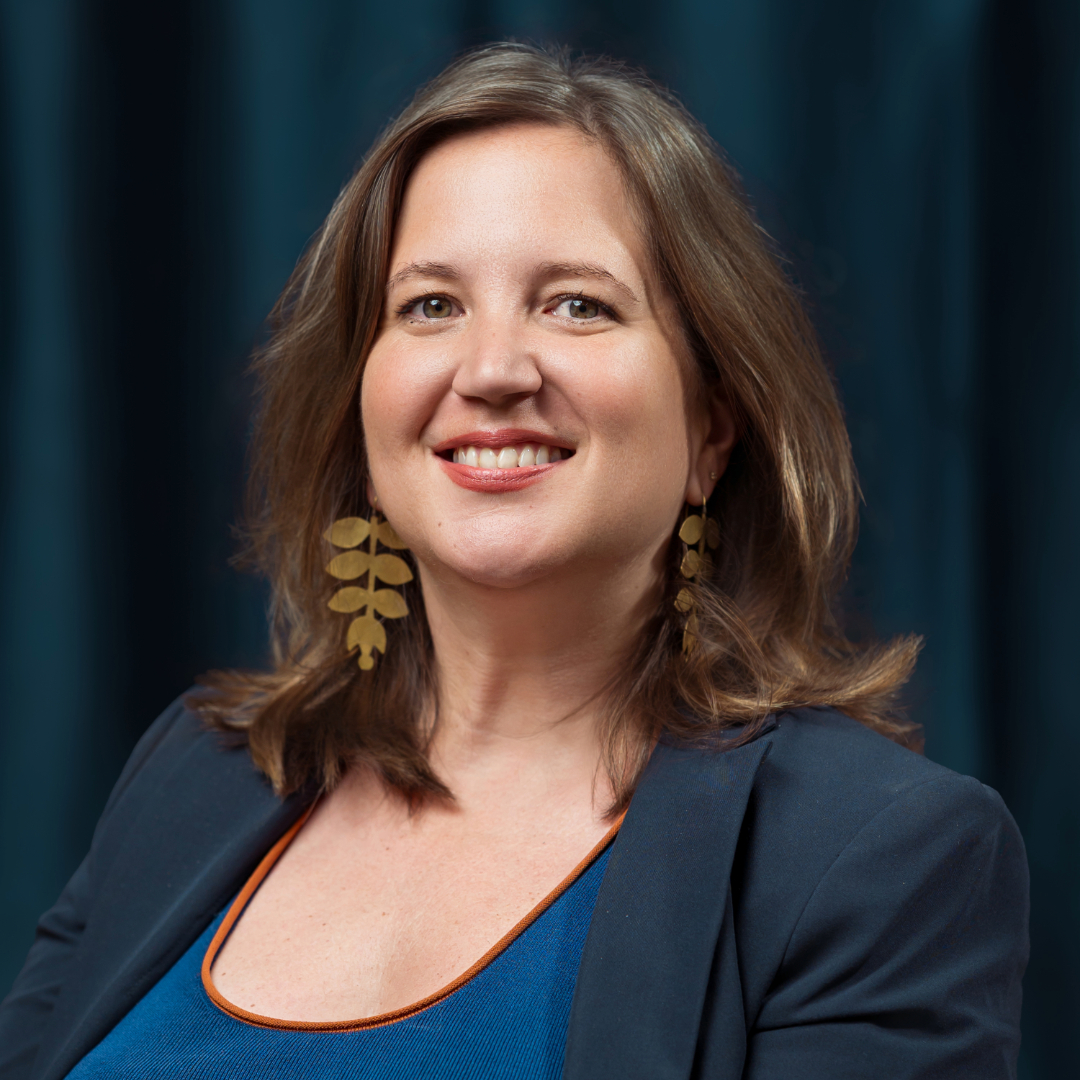 A person with brown hair and large hoop earringsDescription automatically generated